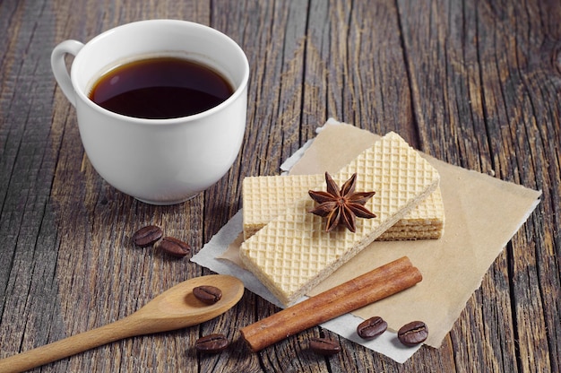 Sweet wafers and cup of hot coffee on dark wooden table