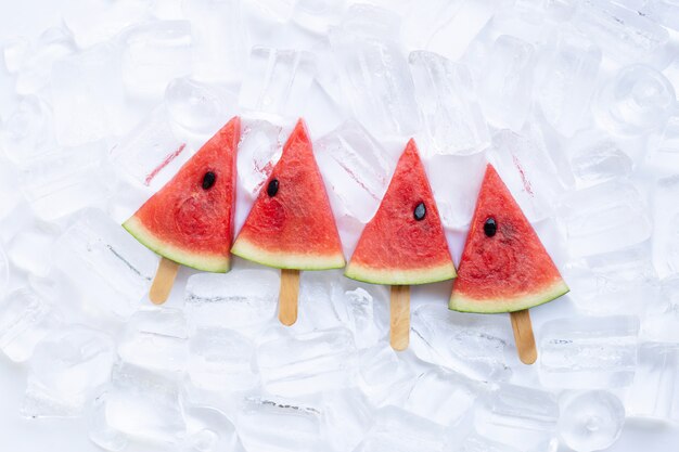 Sweet watermelon slice popsicles on ice background