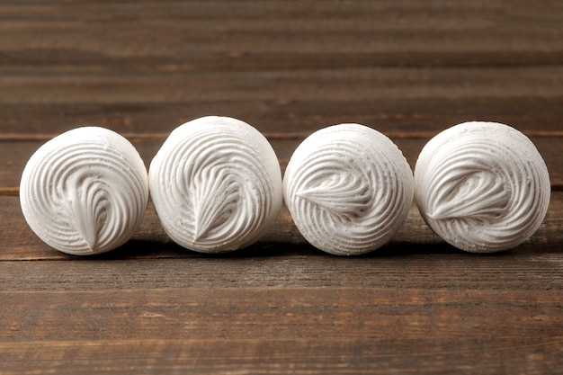 Sweet white round marshmallow on a brown wooden table.