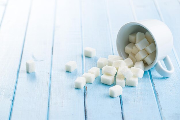 Сладкие кубики белого сахара на синем деревянном столе