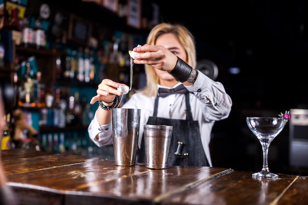 Sweet woman barkeeper makes a show creating a cocktail in pub