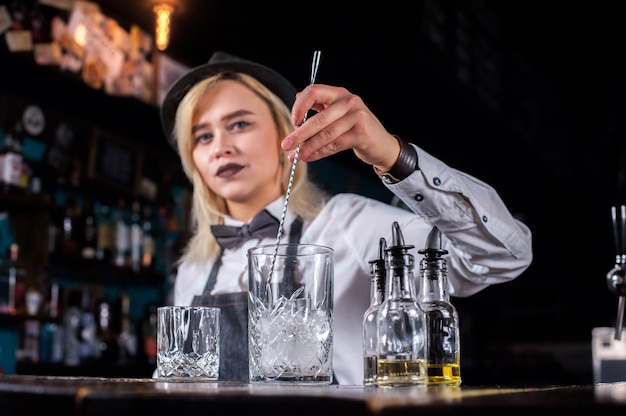 La dolce donna mixologist sorprende con i suoi visitatori del bar delle abilità stando vicino al bancone del bar