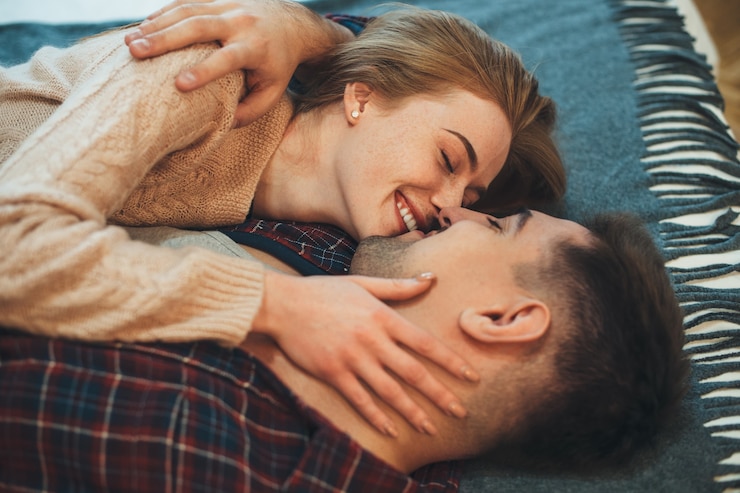 Photo そばかすのある甘い女性がアパートで寒い朝に夫にキスをしている