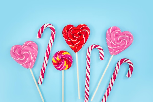 Sweets candies cookies and lollipops on a blue background hearts Christmas canes Top view copy space