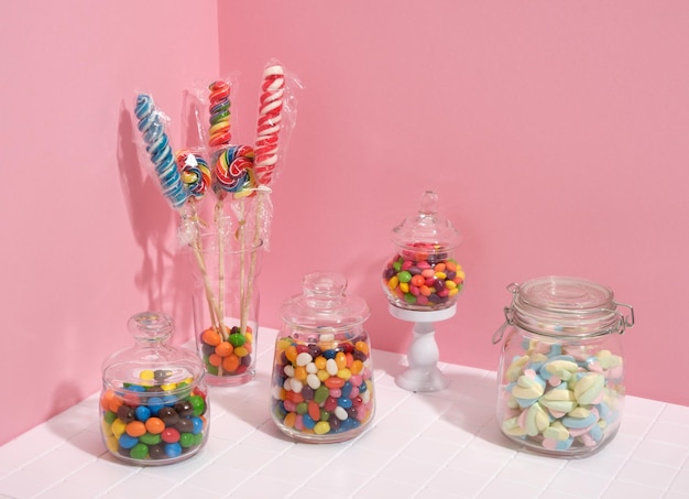 Sweets in different colors and sizes packed in different jars on the holiday table lollipops marshmallows and candy for a cheerful mood