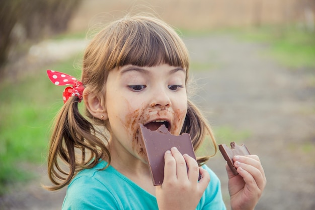 甘い歯の子供はチョコレートを食べる選択的な焦点