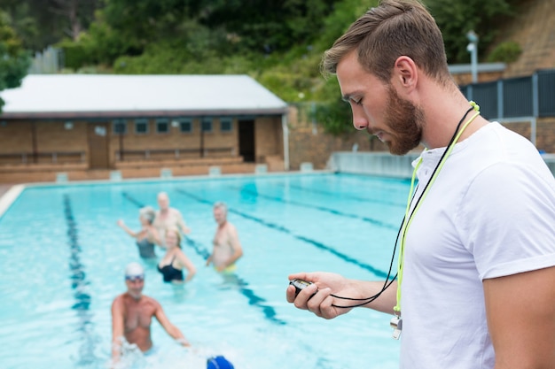 Тренер по плаванию смотрит на секундомер возле бассейна в развлекательном центре