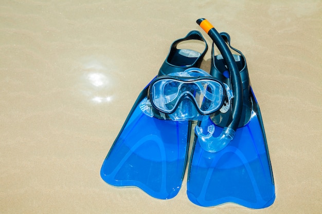 Swim flippers, mask, snorkel, hat in the surf on the sandy beach