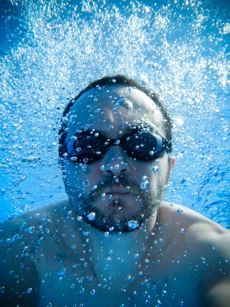 Пловец в очках плавает в бассейне, вид под водой