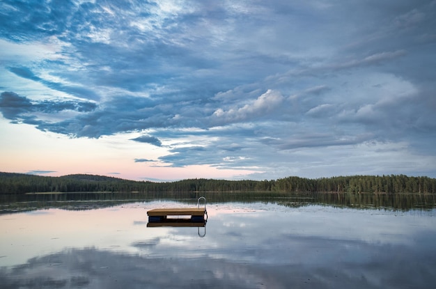 写真 日没時の湖にあるスウェーデンの水泳島水面に映る雲スカンジナビアのレクリエーションで休暇中の水泳の楽しみ
