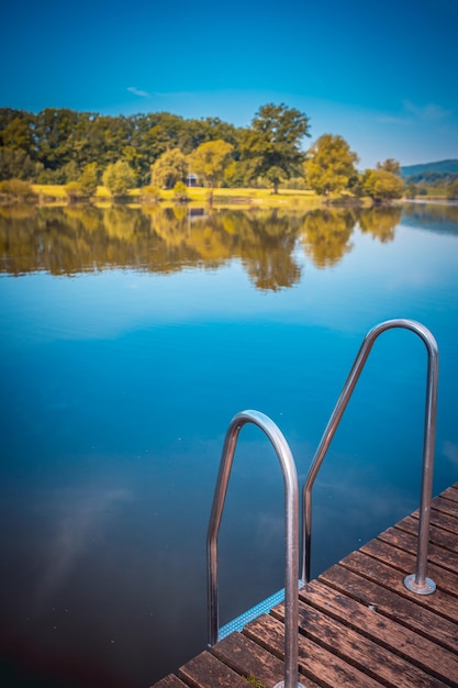 Swimming pool by lake against blue sky