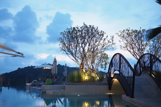 Swimming pool by trees against sky