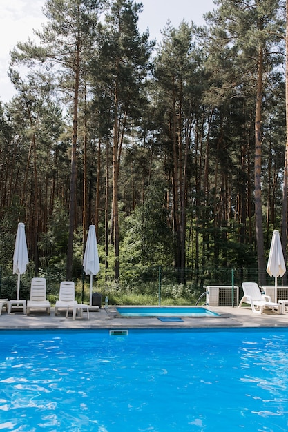 A swimming pool in the forest with umbrellas in summer