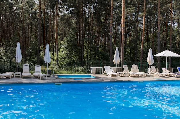 A swimming pool in the forest with umbrellas in summer