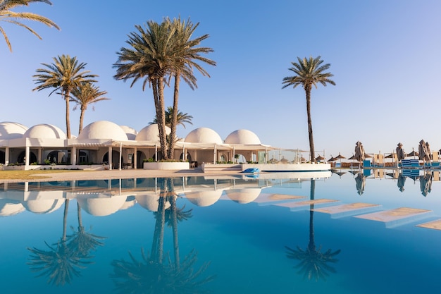 Swimming pool and palm trees with traditional building with dome roof Tunisia