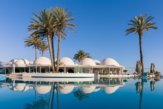 Photo swimming pool and palm trees with traditional building with dome roof tunisia