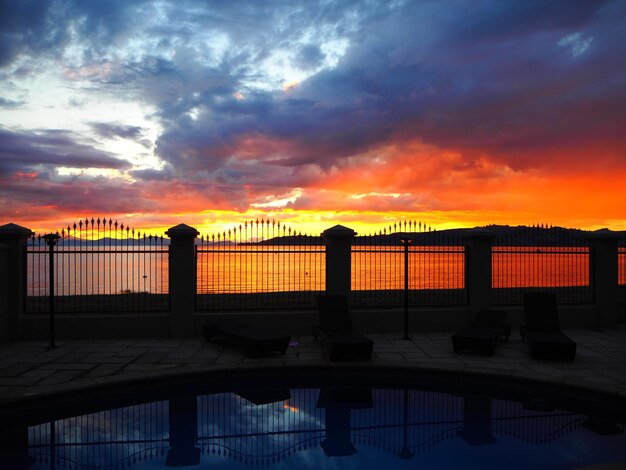 Swimming pool and river against cloudy sky at sunset