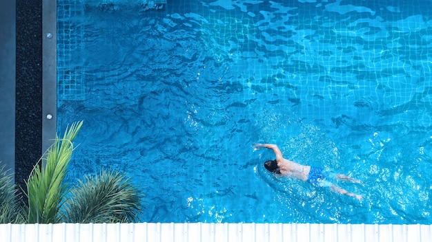 Swimming pool top view angle which young man relaxing and enjoying in pools of his hotel in summer