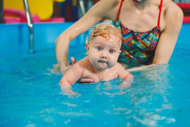 Swimming pool for training newborn children to swim Baby swimming in the pool Teaching a newborn boy to swim in a pool with a coach