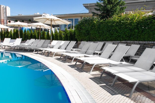 Swimming pool and white chair with white fashion deckchairs on the beach Luxury sunbeds