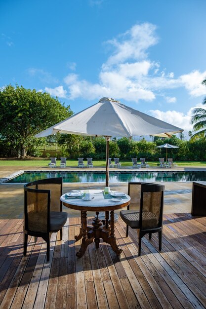 Swimming pool with beach chairs and lunch table at a luxury resort tropical pool