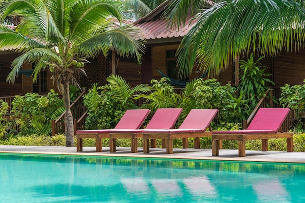 Swimming pool with relaxing beds and green palm trees in tropical garden Thailand