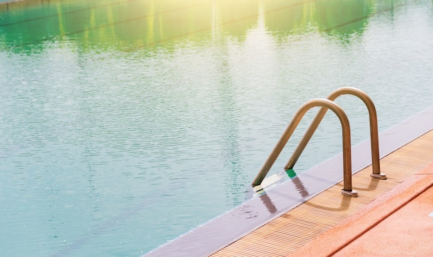 Swimming pool with stair and wooden deck at hotel.