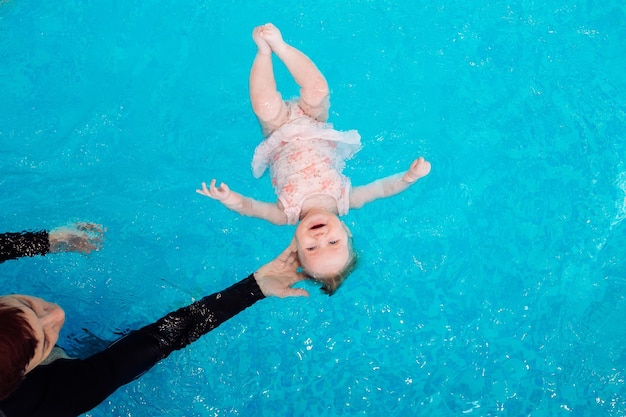 A swimming teacher teaches a kid to swim in the pool.