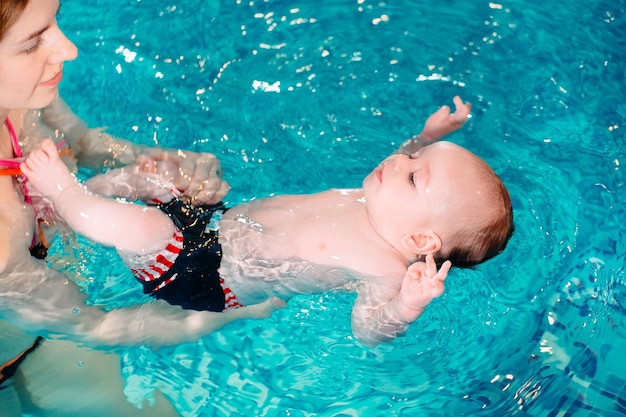 A swimming teacher teaches a kid to swim in the pool