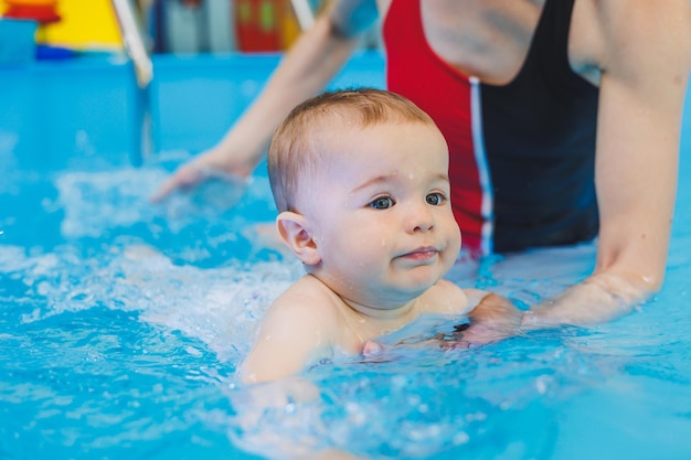 수영 선생님이 어린 소년에게 수영장에서 수영하는 법을 가르칩니다 어린이의 첫 수영 강습 아기를 위한 발달