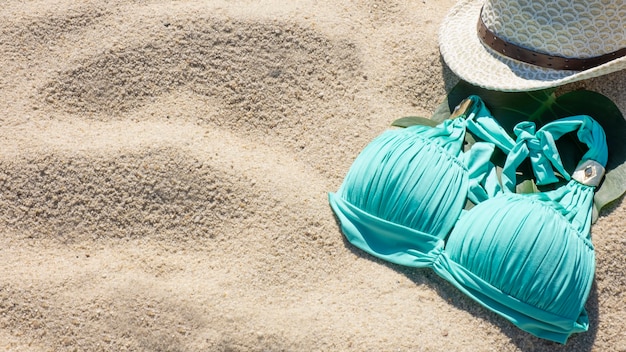 Swimsuit and hat on sandy beach.