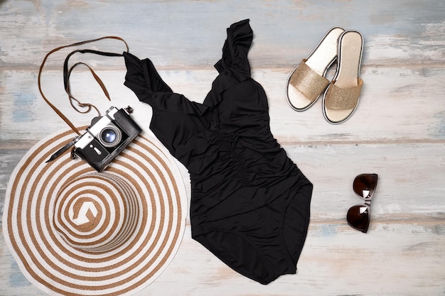 swimsuit, hat, slippers, glasses and an old camera on a wooden background