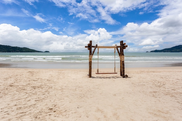 Swing at the beach with clouds on a blue sky landscape