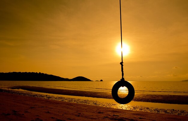 Foto swing appeso sulla spiaggia contro il cielo durante il tramonto