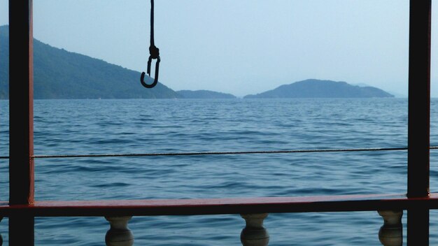 Photo swing hanging over sea against clear sky