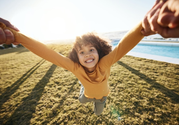 Swing pov portrait of girl and hands of parent in garden spinning and circle movement kid on grass of home for play love and happiness Smile relax and person flying for game and freedom