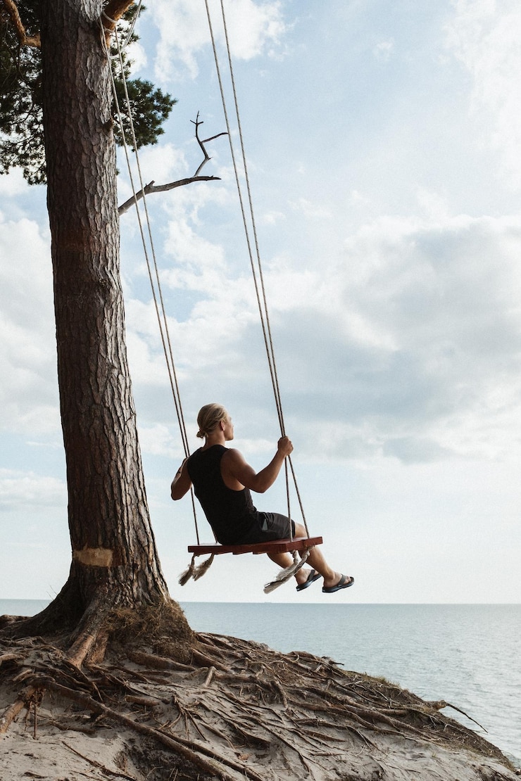 Photo swings on a cliff man lookinga t sea horizon