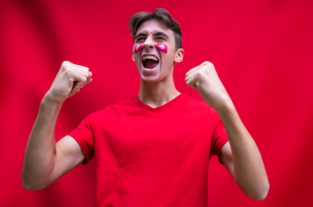 Swiss football fan shouting happy for his national team isolated on red background Flag painted