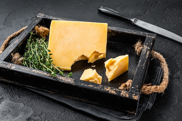 Swiss Hard cheese piece in wooden tray. Black background. Top view.