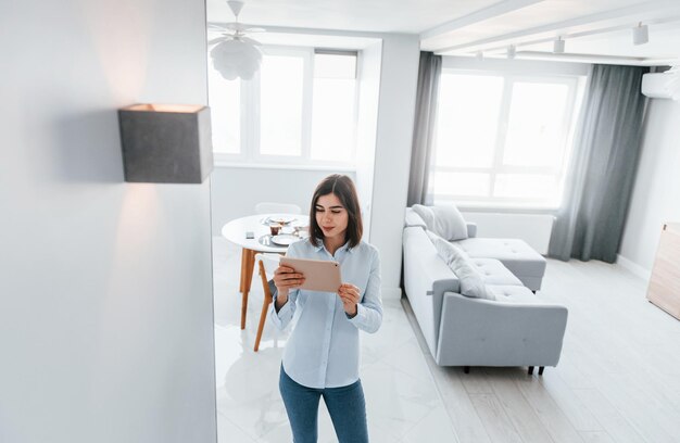 照明を切り替える若い女性は昼間スマートハウスの部屋で屋内にいます