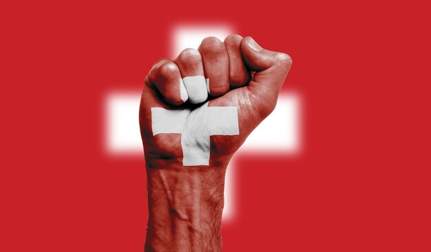 Switzerland flag painted on a clenched fist strength protest concept