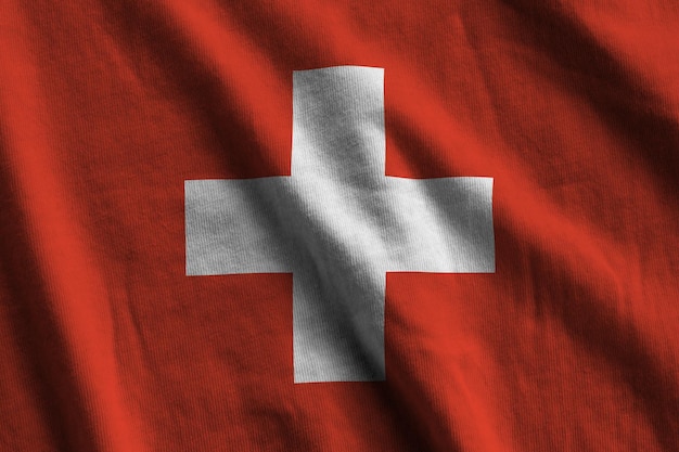 Switzerland flag with big folds waving close up under the studio light indoors The official symbols and colors in banner