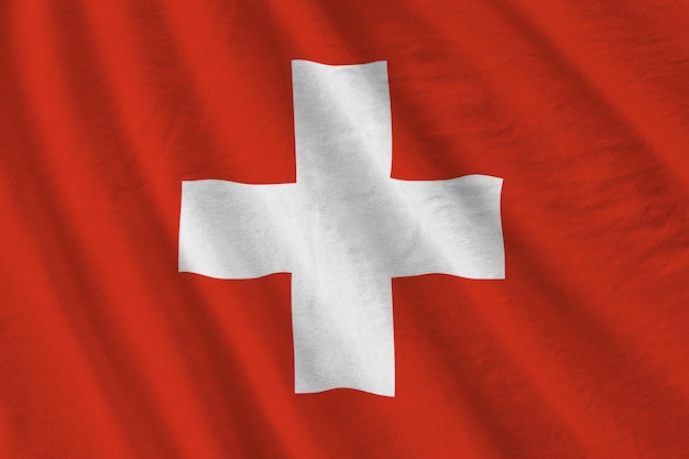 Switzerland flag with big folds waving close up under the studio light indoors The official symbols and colors in banner