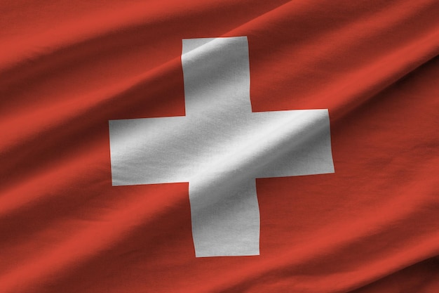 Switzerland flag with big folds waving close up under the studio light indoors The official symbols and colors in banner