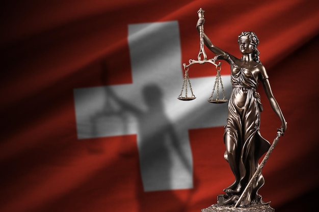 Switzerland flag with statue of lady justice and judicial scales in dark room Concept of judgement and punishment