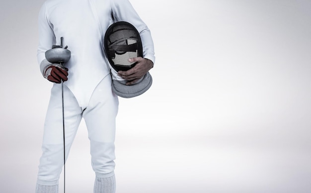 Swordsman holding fencing mask and sword against grey vignette