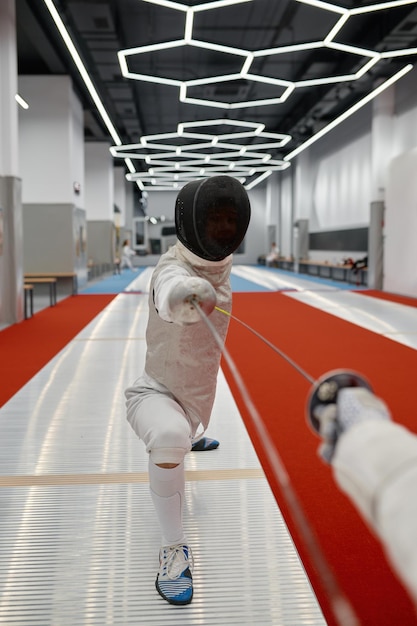 Swordsman standing in fencing lunge during training fight in fencer club