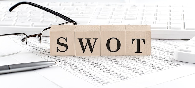 SWOT написан на деревянном кубе с диаграммными очками калькулятора клавиатурыБизнес-концепция