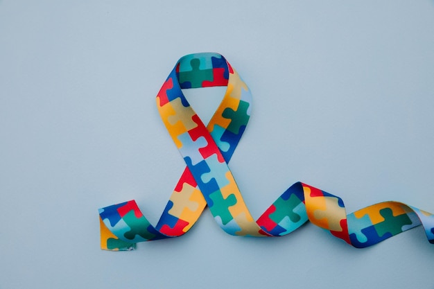 Symbol of autism with Puzzle pattern ribbon on blue background