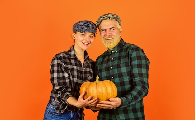 Symbol of the celebration happy man and woman checkered shirt and hat Give Thanks Harvest time Yellow ripe pumpkin Thanksgiving Day with pumpkin Vintage family couple food and harvest